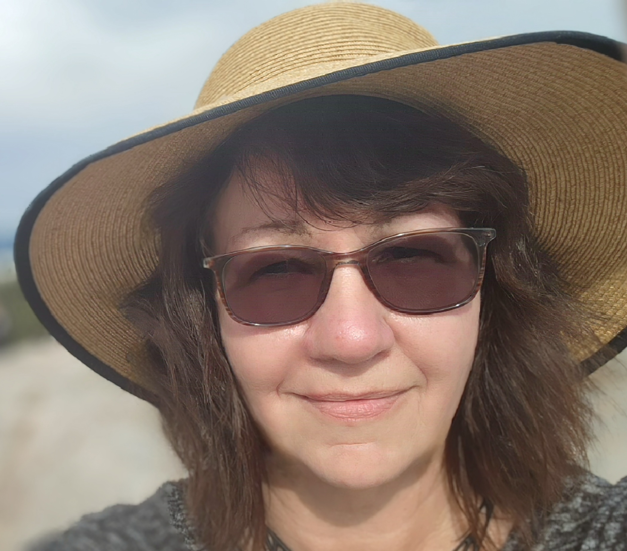 Author Lisa Yoder headshot in a hat and sunglasses. White female with dark brown hair.