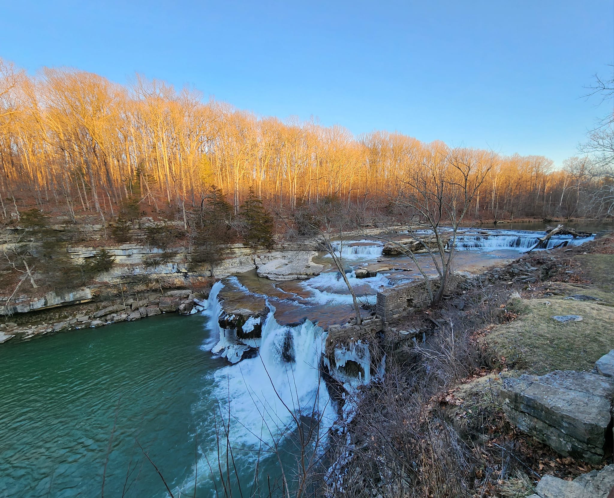 Partially frozen waterfall with evening lighting in the fall.