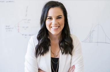 Photo of Your Local Epidemiologist, Dr. Katelyn Jetelina, in a black shirt and white jacket, with long, dark hair, facing the camera. 