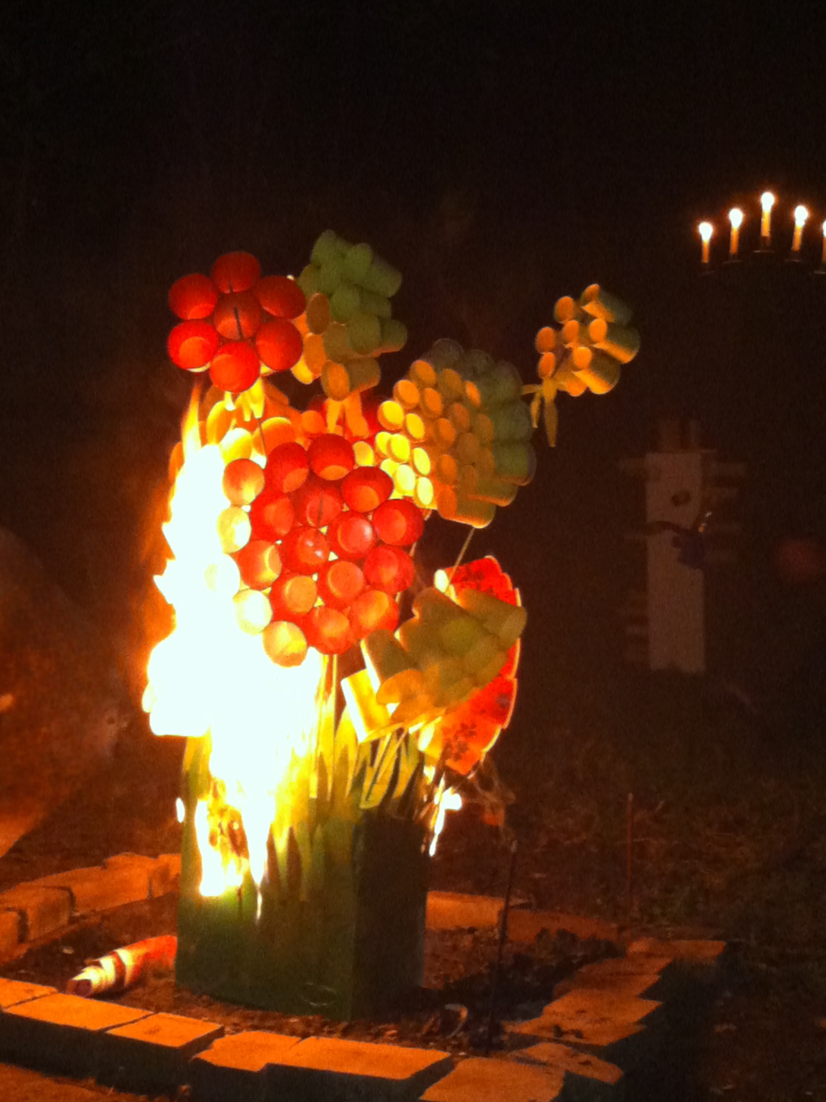 Colorful paper flowers in a box on fire in an outdoor fire pit