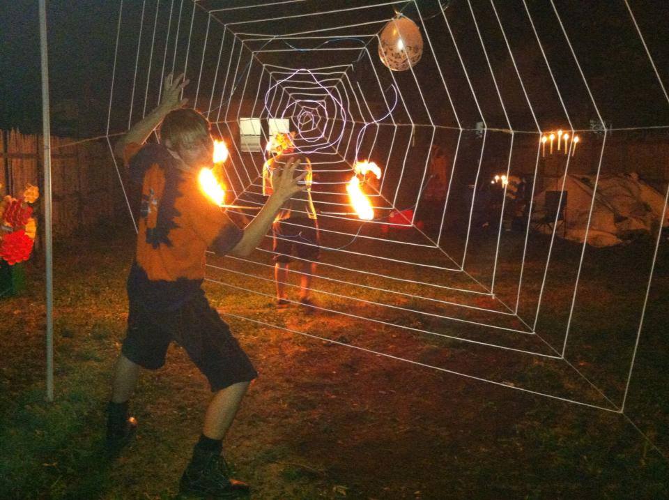 Man grabbing a large strung up spider web in a yard after dark