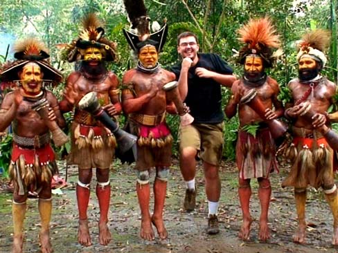 Young, white man dancing outside with tribal dancers in traditional garb in Papua New Guinea