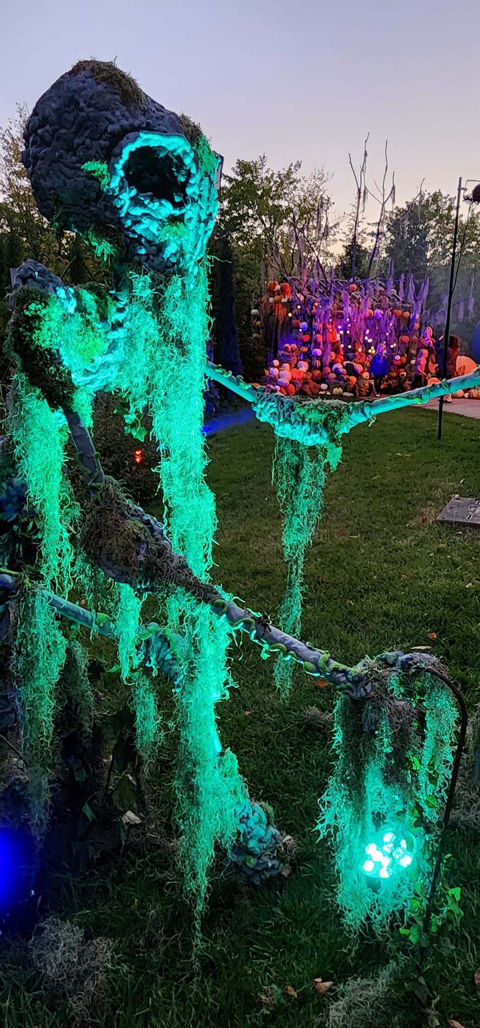 A mossy, green, glowing creature lit at night in an outdoor garden setting