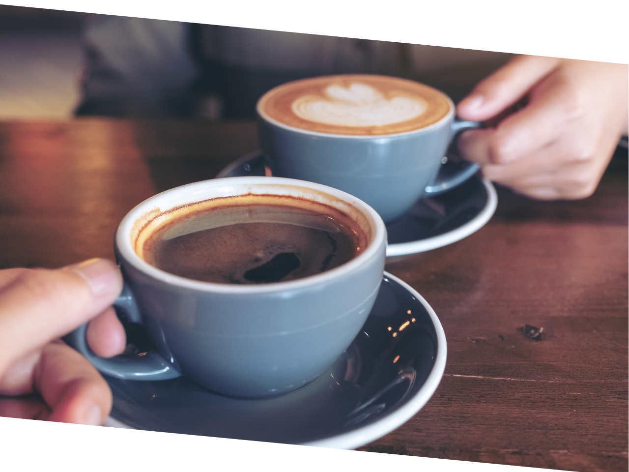 Close up of two cups of coffee with hands holding each one