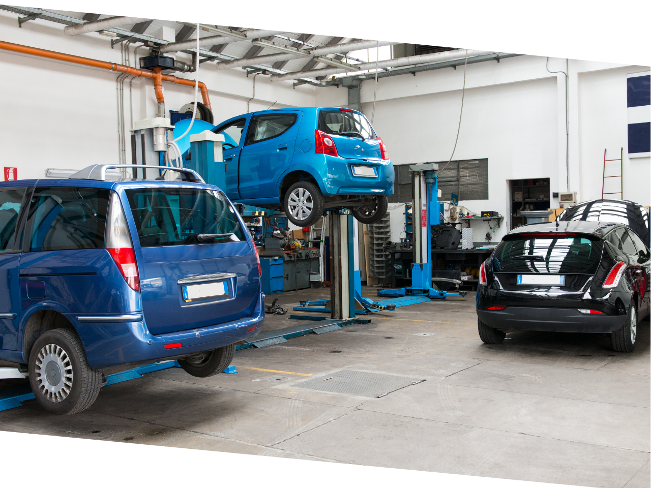 Auto service with one car up on a lift and two others in the shop.