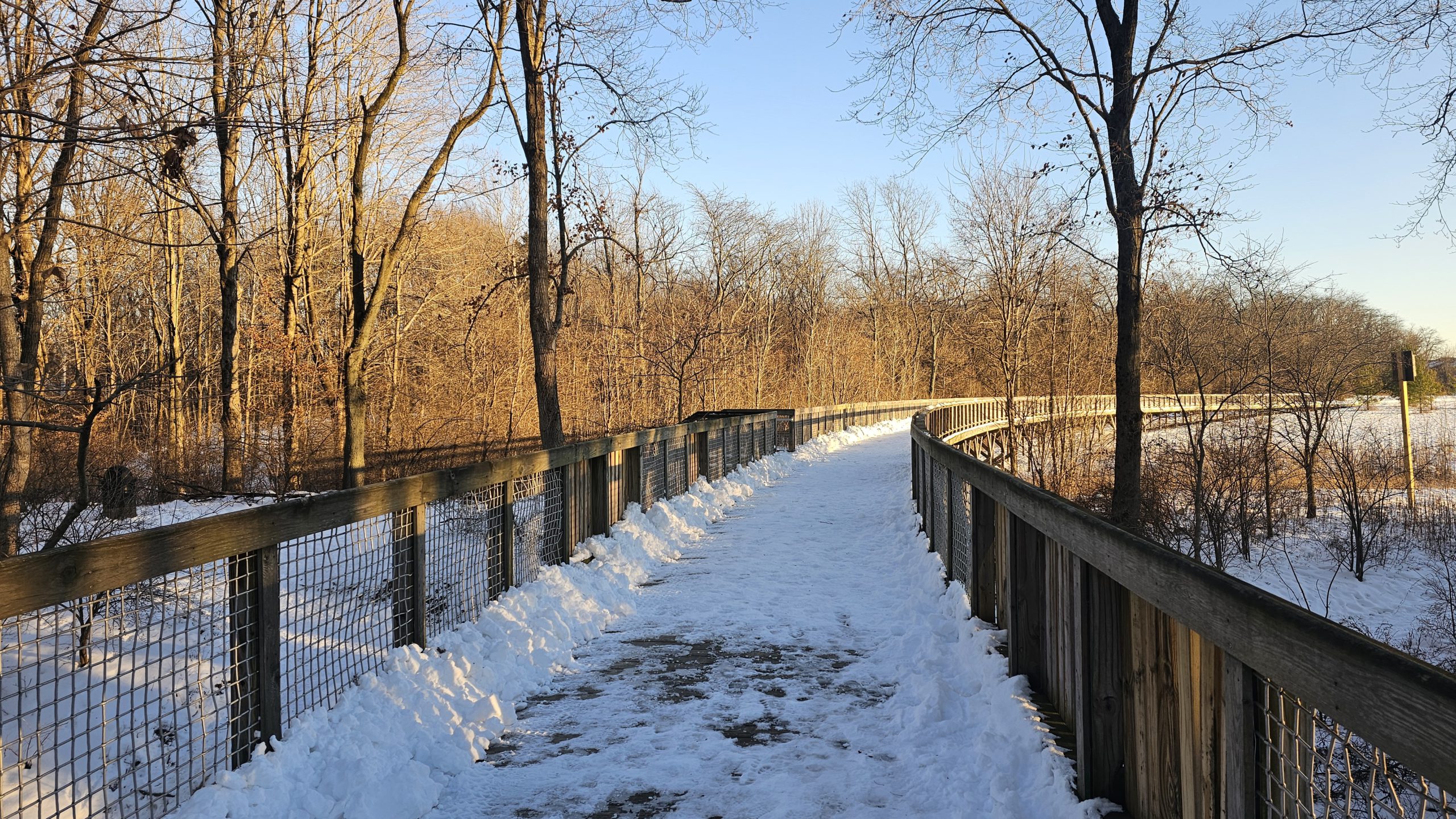 Curved, long bridge path with snow on it in the winter light of evening