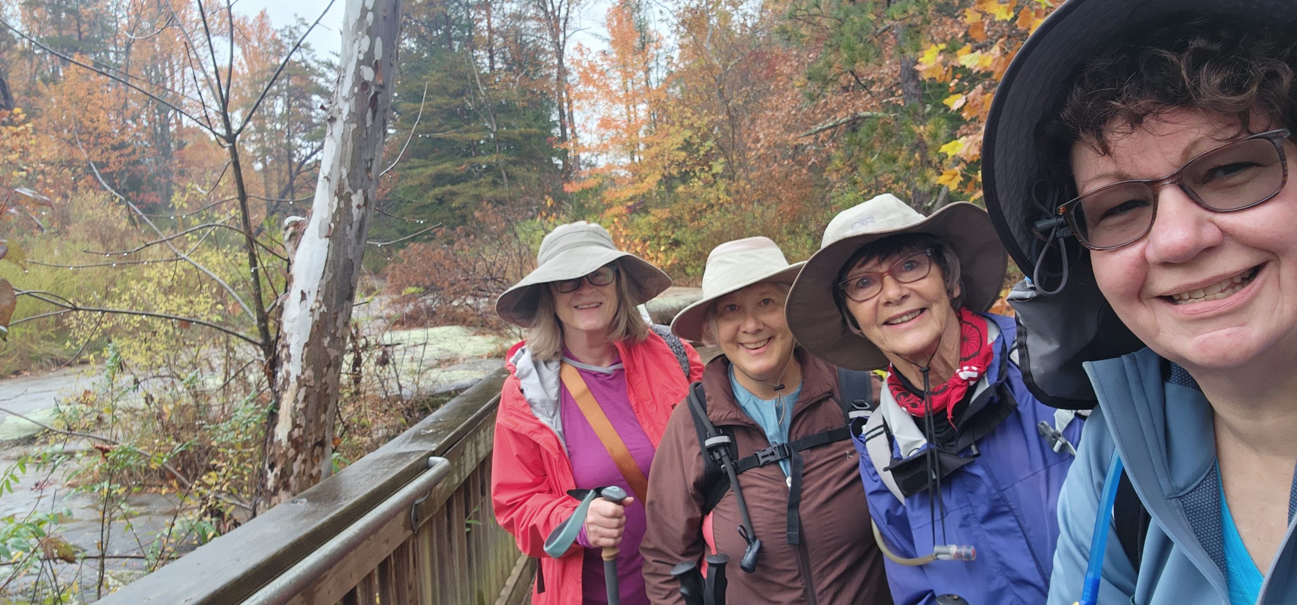 Four women outdoors on a hike together, all lined up facing the camera.